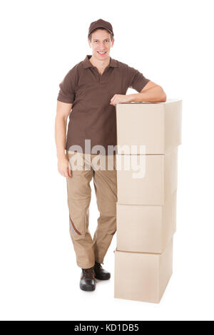 Young Delivery Man sur une pile de boîtes sur fond blanc Banque D'Images