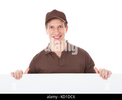 Young Delivery Man Holding Blank Banner over White Background Banque D'Images