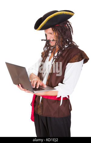 Portrait d'un pirate à l'aide d'ordinateur portable tenant le couteau dans sa bouche Banque D'Images