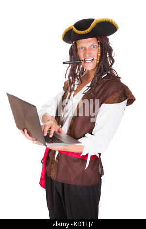 Portrait d'un pirate à l'aide d'ordinateur portable tenant le couteau dans sa bouche Banque D'Images