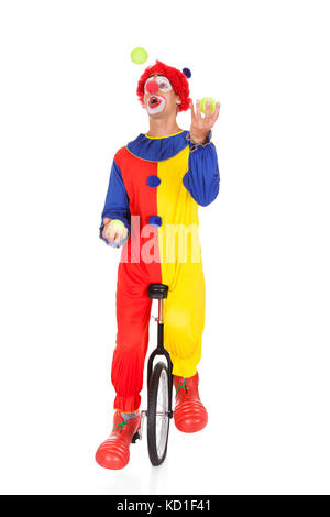 Portrait d'un clown jonglant avec des balles sur Monocycle sur fond blanc Banque D'Images