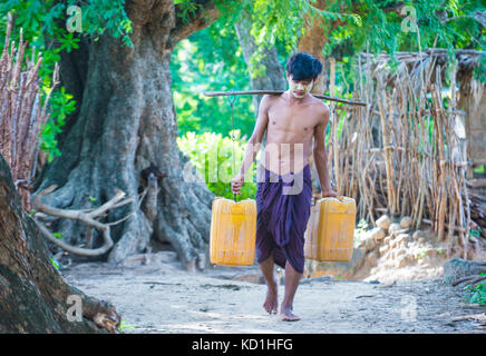 Fermier birman transportant des seaux remplis d'eau dans un village près de Bagan Banque D'Images