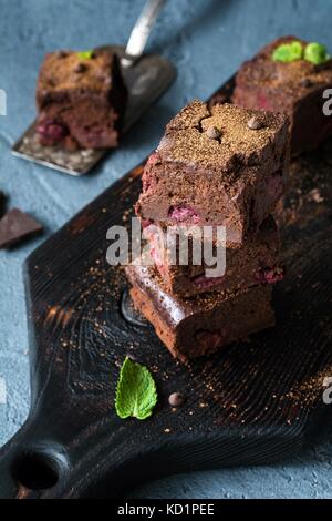 Brownies avec cherry et feuille de menthe sur la planche à découper sombre au point sélective vertical gros plan. Banque D'Images