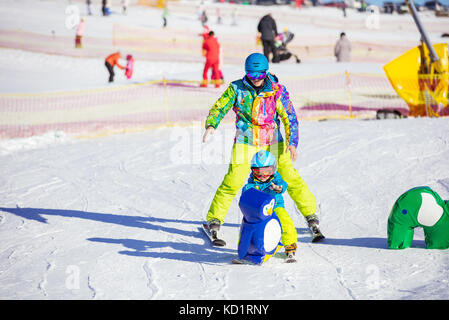 L'enseignement du père petit fils de skier dans la station de sports d'hiver, le garçon s'insérant dans les obstacle jouet Banque D'Images