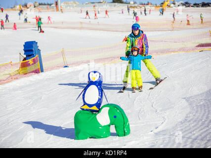 L'enseignement du père petit fils de skier dans la station de sports d'hiver, le garçon doit glisser passé obstacles jouet Banque D'Images