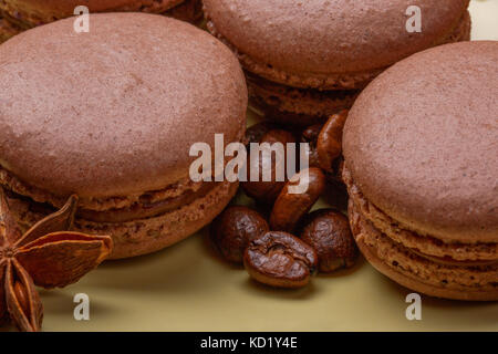 Macarons au chocolat et grains de café torréfié foncé sur fond jaune. Focus sélectif. macro photographie Banque D'Images