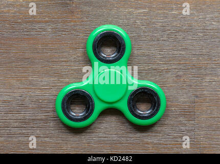 Image de fidget doigt spinner stress toy - spinner vert sur un bureau en bois Banque D'Images