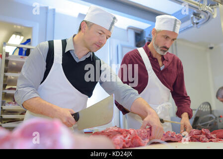 Les bouchers de couper le jambon et la viande fraîche en usine de porc Banque D'Images