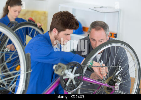 Mécanicien vélo et les apprentis de la réparation d'un vélo à l'atelier Banque D'Images