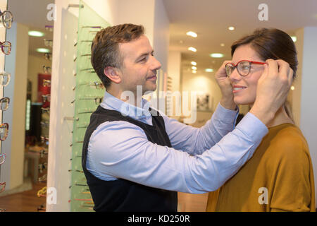 Ophtalmologiste et belle brune femme choisissant en optique lunettes store Banque D'Images