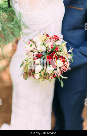 Vue rapprochée de la belle mariage bouquet composé de fleurs colorées et les herbes dans les mains du marié. Banque D'Images