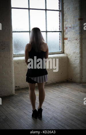 Vue arrière d'une jeune femme portant une jupe courte article par la fenêtre Banque D'Images