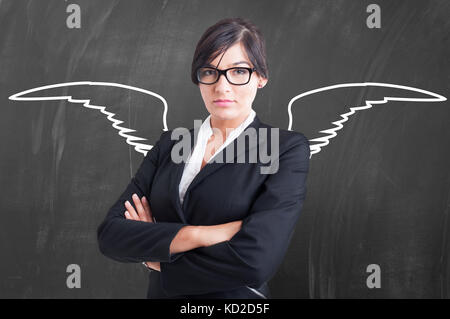 Enseignante ange avec ailes de craie sur tableau noir debout les bras croisés en arrière-plan Banque D'Images