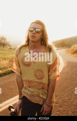 Portrait de jeune homme aux cheveux longs sur les skateur Road, Exeter, California, USA Banque D'Images