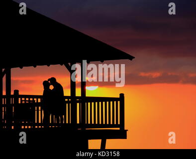 Lovers silhouette sur le coucher du soleil sur une terrasse vole un baiser romantique au format paysage with copy space Banque D'Images