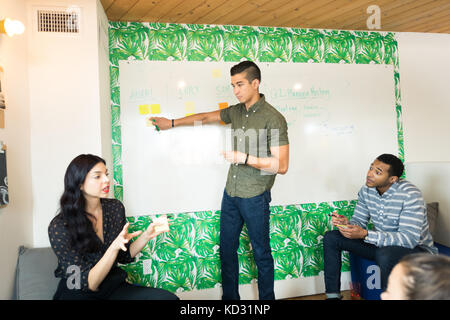 Young businessman pointing at whiteboard dans salle de réunion créative Banque D'Images