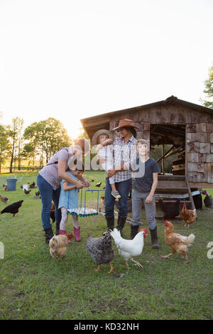 Famille à la ferme, entouré par les poulets, mother and daughter holding tray of oeufs frais Banque D'Images