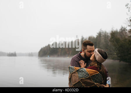 Par couple wrapped in blanket lake s'embrasser, Bancroft, au Canada, en Amérique du Nord Banque D'Images