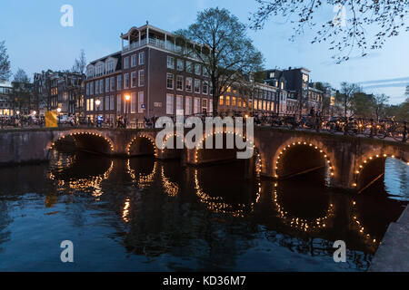 Arches du pont illuminé reflétée dans le canal Herengracht à Amsterdam Banque D'Images