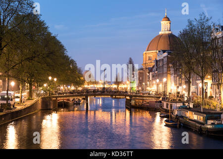 Le canal Singel à Amsterdam, de nuit, avec l'Église luthérienne ronde sur la droite Banque D'Images