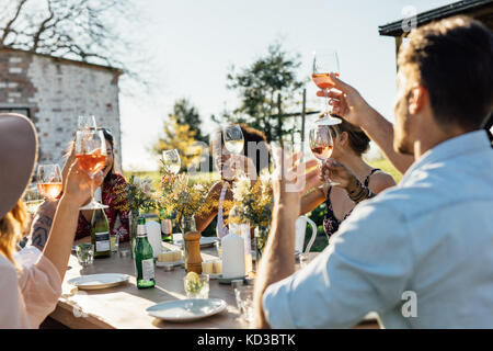 Friends toasting drinks at a party. Les jeunes traîner à l'extérieur restaurant et prendre un verre. Banque D'Images