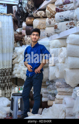 La province du Fars, Shiraz, Iran - 19 avril, 2017 : un jeune Iranien vendeur de tissu est debout dans un magasin de textile dans la ville bazar. Banque D'Images