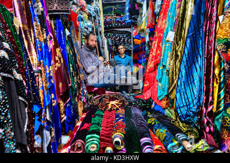 La province du Fars, Shiraz, Iran - 19 avril 2017 : deux vendeurs de tissus iraniens sont assis dans une boutique de textile dans la ville bazar. Banque D'Images