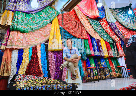 La province du Fars, Shiraz, Iran - 19 avril, 2017 : un seul vendeur est assis sur un banquet dans le département textile du marché. Banque D'Images