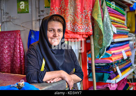 La province du Fars, Shiraz, Iran - 19 avril, 2017 : un portrait d'un inconnu, d'une iranienne mature vêtue d'un hijab, la vente de tissus colorés dans une matière textile Banque D'Images