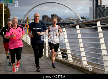 Le Premier ministre adjoint John Swinney (au centre) dirige le « Conference Mile » le long de la rivière Clyde avec Hannah Bardell MP (à gauche) et Ivan McKee MSP (à droite) après avoir assisté à la conférence du Parti national écossais au SEC Center à Glasgow. Banque D'Images