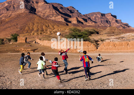 Maroc-DEC 27, 2012 : les garçons jouent avec un ballon de soccer sur un champ de terre. Lieu : Vallée du Drâa village. Le football est le sport numéro 1 chez les jeunes au Maroc Banque D'Images