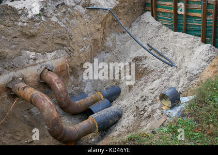 L'eau grand métal acier tuyaux pvc sol en tranchée à ciel ouvert lors de fossé en construction Plomberie Réparation Banque D'Images