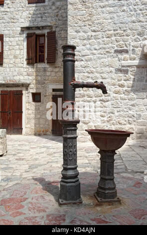 Une colonne de distribution d'eau avec un bol sur la rue de la vieille ville de Kotor Banque D'Images