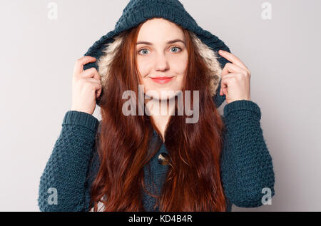 Une belle femme heureuse avec des cheveux longs vêtu d'étoffes de couleur bleu-vert ou noir manteau avec une capuche réchauffé avec fourrure blanche. girl regarde droit à s Banque D'Images