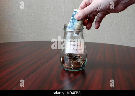 Ajouter de l'argent à la Pension Pot pot bocal en verre sur la table épargne-retraite la pauvreté financière des temps difficiles Banque D'Images