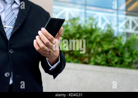 Businessman se tenir en face de l'office buliding avec l'arbre de la feuille verte Banque D'Images