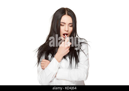 Studio portrait de fille brune sur blanc, de la détention et de l'utilisation de spray pour la gorge, médicament anti grippe aviaire. Notion de maladie,virus, la respiration et l'esprit de soins Banque D'Images