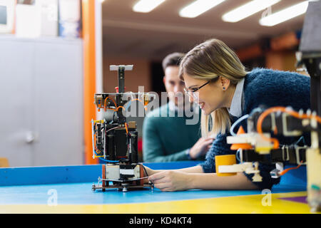 Jeune ingénieur à l'essai son robot en atelier Banque D'Images