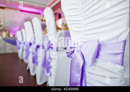 Photo en gros plan de violette petits nœuds attachés sur les chaises dans le restaurant. Banque D'Images