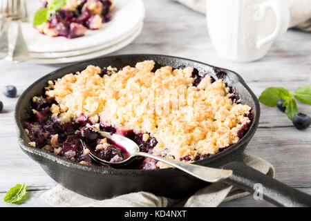 Crumble de noix de coco dans la poêle en fonte avec des pommes fraîches et de bleuet. alimentation saine concept. Banque D'Images