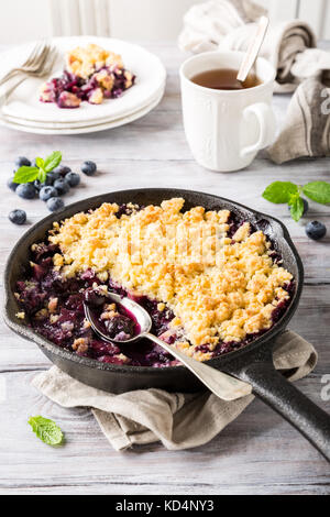 Crumble de noix de coco dans la poêle en fonte avec des pommes fraîches et de bleuet. alimentation saine concept. Banque D'Images