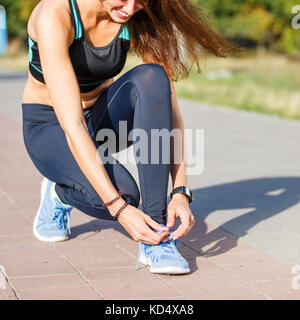 Jeune femme runner attacher ses lacets sur le sentier de jogging park Banque D'Images