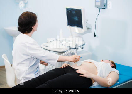 Femme enceinte à ultrasons à coups de son bébé en pleine croissance a montré par son médecin lors de l'examen médical Banque D'Images