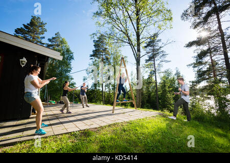 Collaborateurs multiethnique de l'équilibre des cordes de traction sur structure en bois femme à patio en forêt Banque D'Images