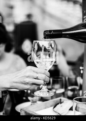 L'image monochrome noir et blanc de verser le vin blanc dans un verre à vin d'une bouteille dans un paramètre extérieur ou ourdoor Banque D'Images