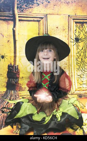 Adorable petite fille à l'halloween le temps. Elle a cinq ans et tenant une boule de feu magique. Banque D'Images