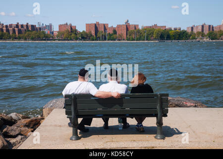 Deux homme juif et une femme assise sur un banc public sur la journée ensoleillée près de l'East River à New York Banque D'Images