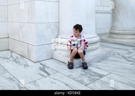 Washington DC-25 mai 2015 : enfant non identifié est titulaire d'un drapeau américain sur le jour du souvenir à l'amphithéâtre memorial en marbre blanc au cimetière d'Arlington. Banque D'Images