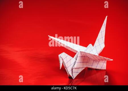 La grue d'origami sur fond rouge