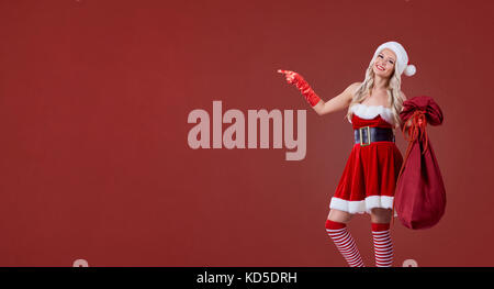 Une petite fille en costume de Père Noël avec un sac de cadeaux un Noël rouge retour Banque D'Images